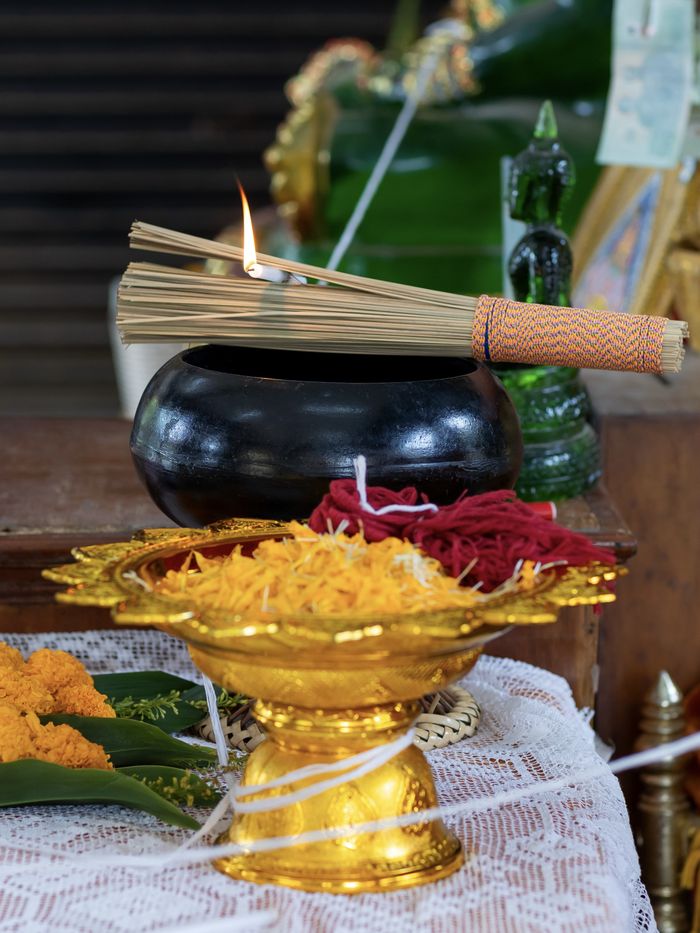 Thai offering bowl with marigolds and incense on a market table in Koh Samui